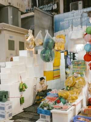 A vibrant market stall featuring a woman surrounded by colorful goods, creating a lively marketplace scene.