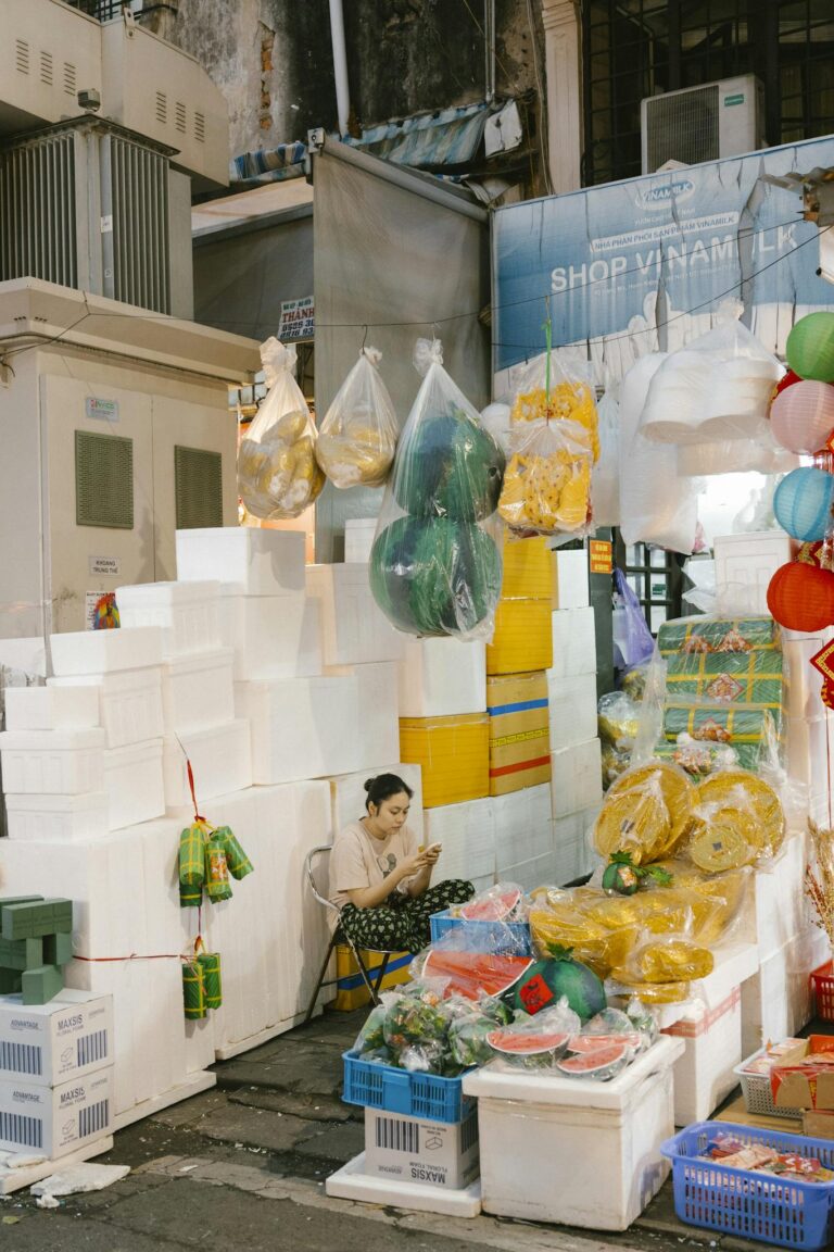 A vibrant market stall featuring a woman surrounded by colorful goods, creating a lively marketplace scene.
