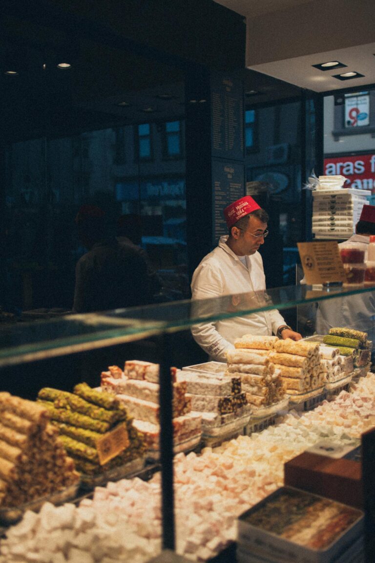 Man selling traditional Middle Eastern sweets at an indoor market stall.
